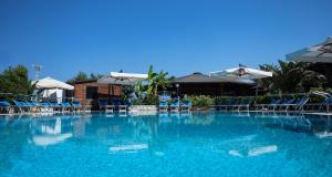 a large swimming pool with blue chairs and umbrellas at Hotel Residence Riviera Calabra in Zambrone