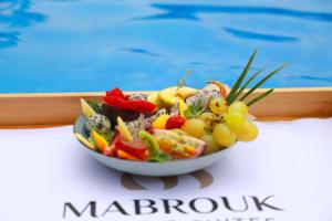 a bowl of fruit on a table next to a pool at Mabrouk Hotel and Suites- Adult only in Agadir
