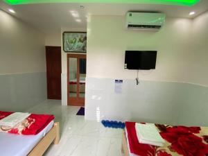 a room with two beds and a tv on the wall at Hoang Anh Hotel in Dĩ An