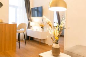 ein Wohnzimmer mit einer Blumenvase auf dem Tisch in der Unterkunft Mint@Naschmarkt Premium Apartments in Wien