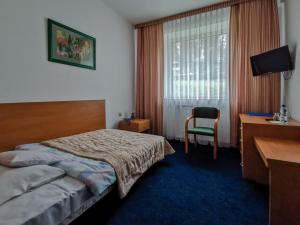 a hotel room with a bed and a desk and a window at Geovita Wisła in Wisła
