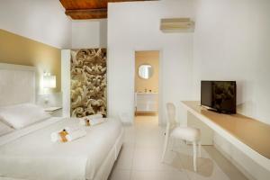 a white bedroom with a bed and a desk with a television at Villa Principe Di Belmonte in Ispica