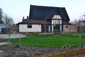 a house with a black roof and a yard at Wortwell Hall Barn in Harleston
