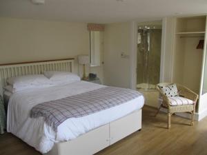 a bedroom with a large bed and a chair at The Red Barn in Long Wittenham