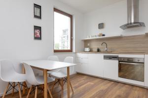 a kitchen with white cabinets and a table and chairs at Royal Wilanów Stylish Apartment in Warsaw