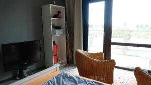 a living room with a flat screen tv and two chairs at Guestroom with wide view and pool near city side, 2nd guest with extra bed possible in Frankfurt/Main
