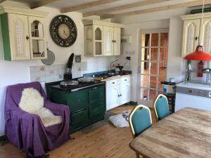 a kitchen with a table and a clock on the wall at Beautiful Highland 1-Bed Cottage in Inverness
