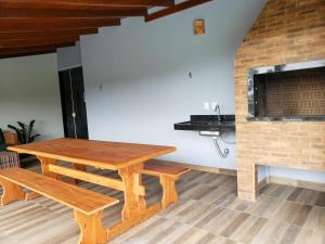 una mesa de madera y un banco en una habitación con chimenea en Casa de temporada com piscina, en Florianópolis