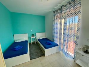 2 letti in una camera con pareti blu e finestra di Villa Viva a Asprouliánoi Altre 37 foto