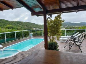 una terraza con sillas y una piscina en una casa en Casa de temporada com piscina, en Florianópolis