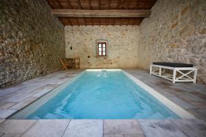 una gran piscina cubierta en un edificio de piedra con una mesa en el centro en Mas de Coulet en Brissac