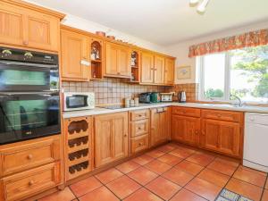uma cozinha com armários de madeira e piso em azulejo em Charming 2 Bed House near Rhoscolyn DISCOUNTS FOR em Holyhead