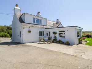 a white house with two chairs on a driveway at Charming 2 Bed House near Rhoscolyn DISCOUNTS FOR in Holyhead