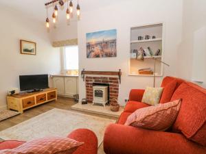 a living room with a red couch and a fireplace at Charming 2 Bed House near Rhoscolyn DISCOUNTS FOR in Holyhead