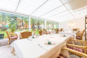 restauracja z białymi stołami, krzesłami i oknami w obiekcie B&B Grüne Laterne - Lanterna Verde w mieście Sesto