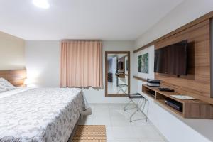 a bedroom with a bed and a flat screen tv at Hotel Tavares Correia in Garanhuns