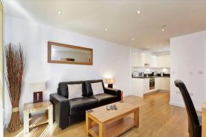 ein Wohnzimmer mit einem schwarzen Sofa und einem Tisch in der Unterkunft MODERN APARTMENT at SLOUGH STATION, LONDON IN 18 MINS! in Slough