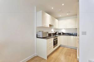 a white kitchen with white cabinets and appliances at MODERN APARTMENT at SLOUGH STATION, LONDON IN 18 MINS! in Slough