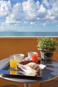 een tafel met een dienblad met brood en drankjes op een balkon bij Hotel il Delfino in San Vincenzo