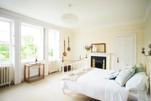 a white bedroom with a bed and a fireplace at Percy Place Bath in Bath