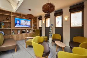 a waiting room with chairs and a flat screen tv at Kyriad La Roche Sur Yon in La Roche-sur-Yon