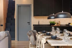 a dining room with a table and a kitchen with black cabinets at HelloChalet - Chalet Northern Lights - Family Ski Chalet with garden walking distance lift in Valtournenche