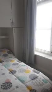 
a bed with a white blanket and a window at Apartment Van Hecke in Blankenberge
