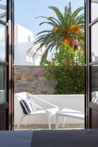 a patio with two white chairs and a palm tree at Aella Residence in Naousa