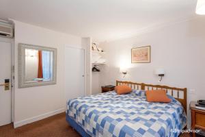 um quarto com uma cama azul e branca e um espelho em Hôtel La Sanguine em Paris