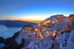 a village on the side of a hill at sunset at Katerina's Castle - Caldera Cave Hotel in Imerovigli
