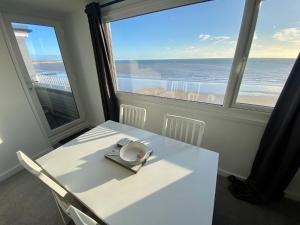 Bridlington Bay Apartments في بريدلينغتون: طاولة بيضاء وكراسي مطلة على المحيط