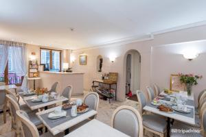 a dining room with tables and chairs and a kitchen at Hôtel La Sanguine in Paris