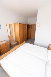 una camera con letto bianco e armadi in legno di Gasthof Kirchberger a Fürth