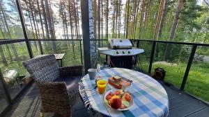 a table with a plate of fruit and a grill on a deck at Kullasmarina Holiday Villas in Padasjoki