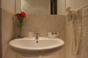 a bathroom sink with a vase of flowers and a phone at Hotel Mediterraneo in Civitavecchia