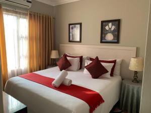 - une chambre dotée d'un grand lit avec des oreillers rouges et blancs dans l'établissement Bay Sun Lodge, à Richards Bay