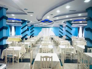 uma sala de jantar com mesas e cadeiras brancas em Hotel Lakaj em Velipojë