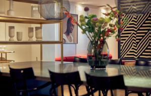ein Esszimmer mit einem Tisch und einer Blumenvase darauf in der Unterkunft Kimpton De Witt Amsterdam, an IHG Hotel in Amsterdam
