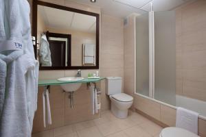 
a bathroom with a toilet, sink and mirror at NH Ciudad de Santander in Santander
