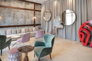 a living room with a couch and chairs and mirrors at NH Collection León Plaza Mayor in León