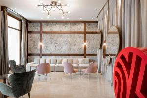 a living room with a white couch and pink chairs at NH Collection León Plaza Mayor in León