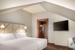 a bedroom with two beds and a flat screen tv at NH Collection León Plaza Mayor in León