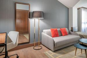 a living room with a couch and a mirror at NH Collection León Plaza Mayor in León