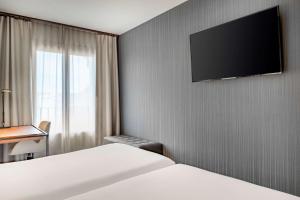a hotel room with two beds and a flat screen tv at NH Collection León Plaza Mayor in León