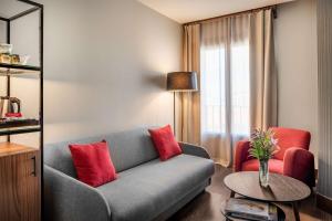 a living room with a gray couch and red pillows at NH Collection León Plaza Mayor in León