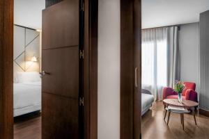 a room with a bedroom with a bed and a table at NH Collection León Plaza Mayor in León