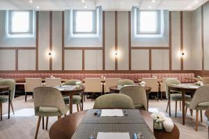 a dining room with tables and chairs and windows at NH Collection León Plaza Mayor in León