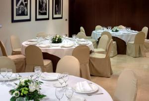 a room with tables and chairs with wine glasses on them at NH Collection León Plaza Mayor in León