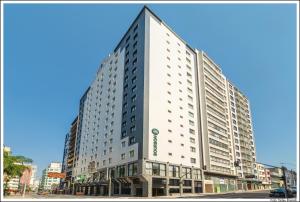 um edifício branco alto numa rua da cidade em Bourbon Curitiba Hotel & Suítes em Curitiba