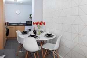 a white kitchen with a white table and white chairs at The Bootlace Apartment in Leicester